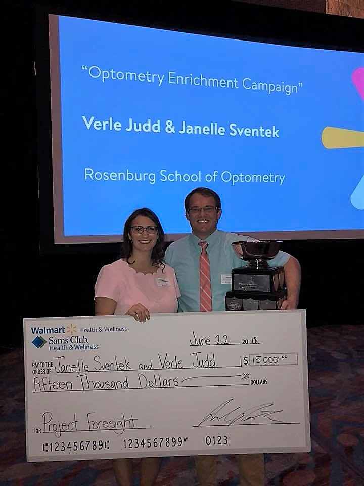 two people standing with a giant check