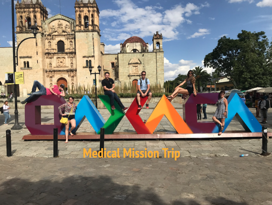 Students posing on a metal installation piece that spells Oaxaca